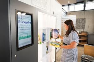 Frau stellt Bücher in Rückgaberegal