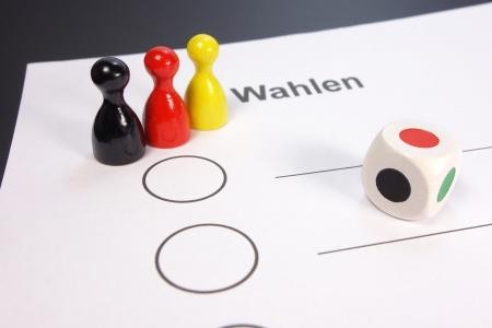 Stimmzettel mit Figuren und Würfel Stimmzettel mit drei Spielfiguren in schwarz, rot und gelb und ein Würfel.