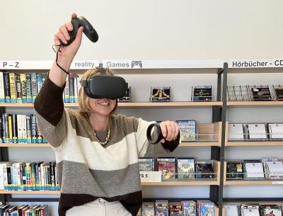 Frau trägt VR Brille und hat Controller in der Hand
