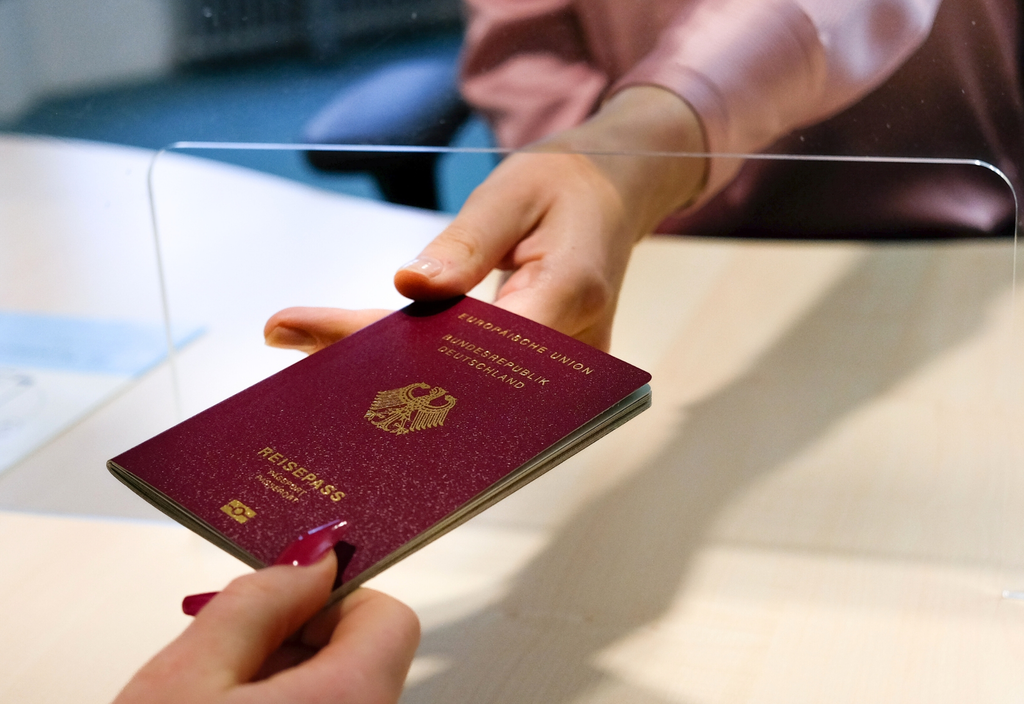 Eine Hand übergibt einen Reisepass